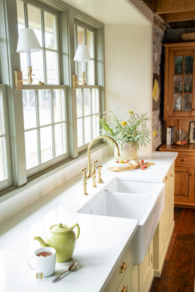 green painted windows with creamy khaki cabinets in a kitchen with marble counter