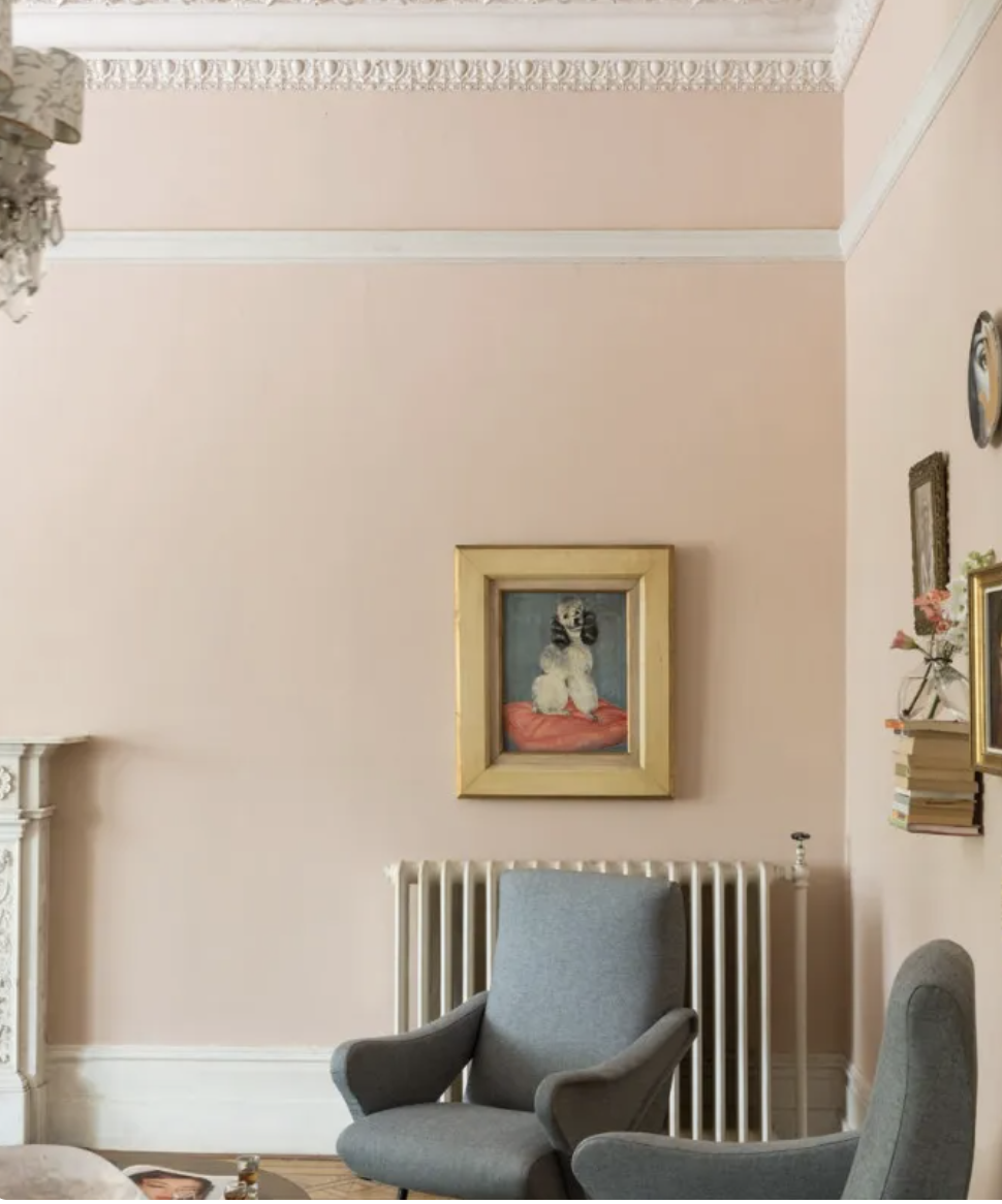 Setting plaster walls with white moulding with two gray chairs and gold framed art