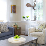 a blue and white living room with a blue sofa, greige walls and decorative accents in greens
