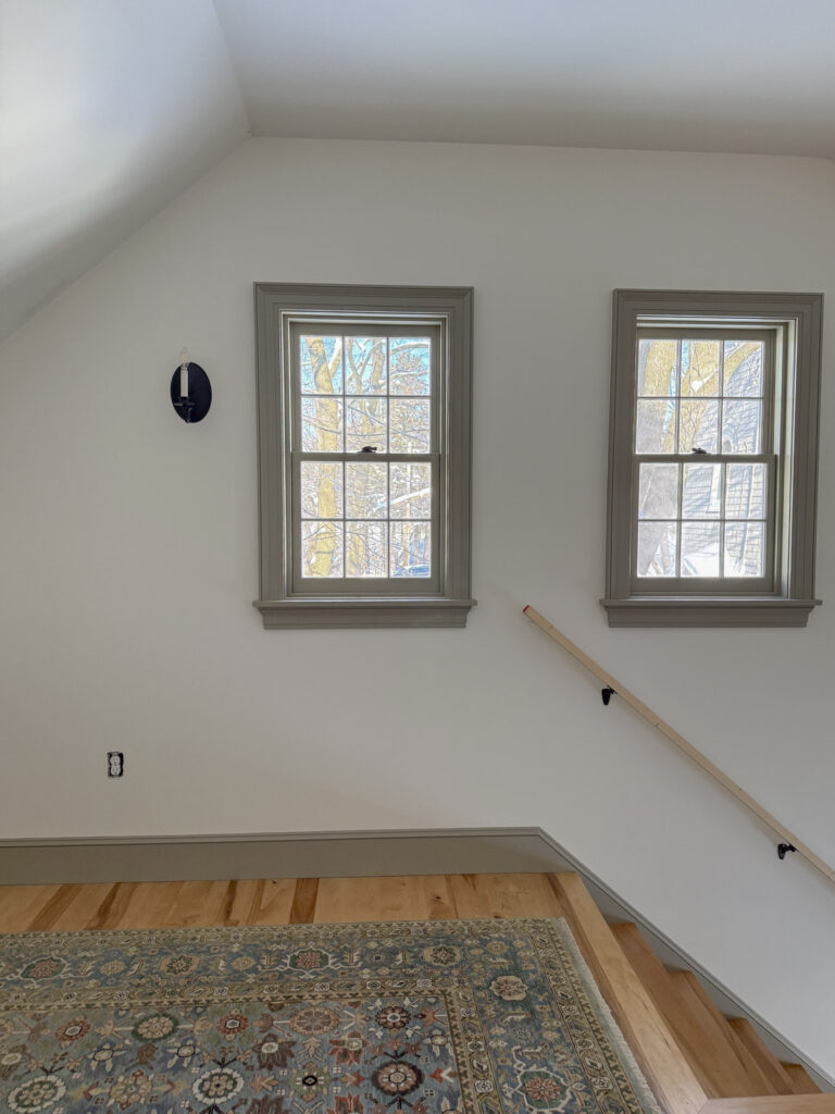taupe windows with a blue gray area rug and maple floor