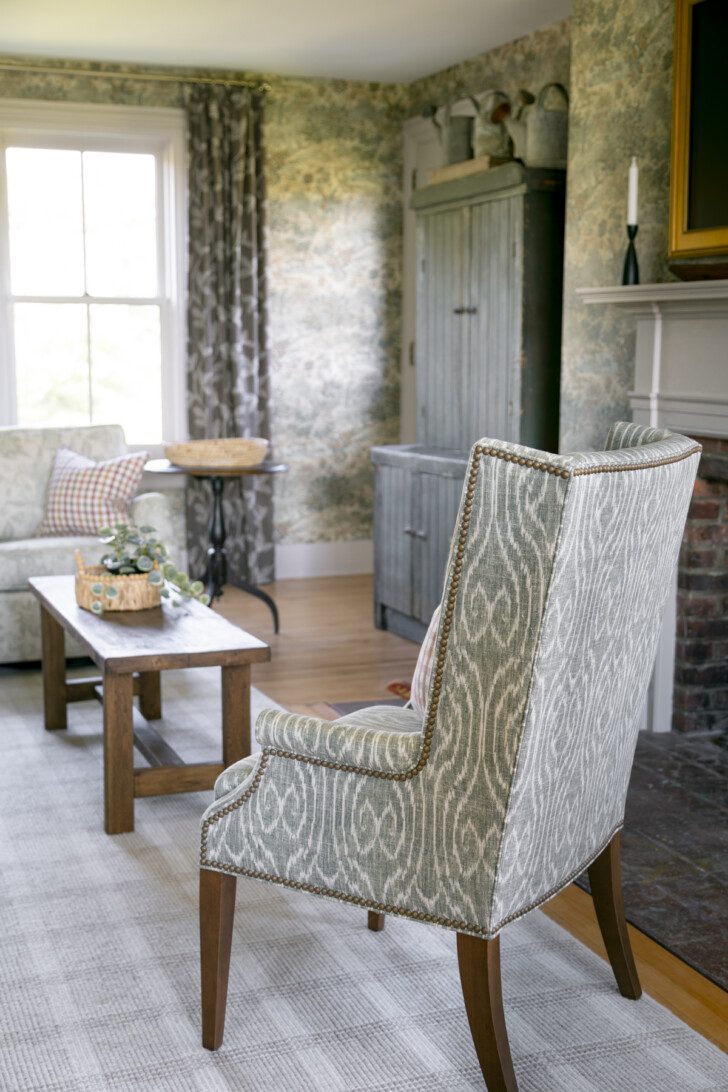 a green upholstered chair with fauxbois pattern and nail head trim